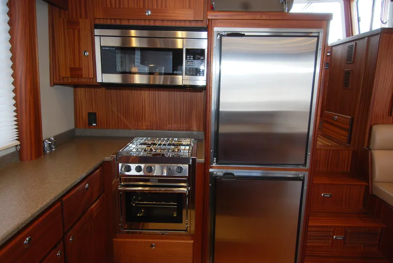 Slide: The Image of Galley kitchen in 2015 American Tug 485 with stainless steel appliances and wood cabinetry. - 34