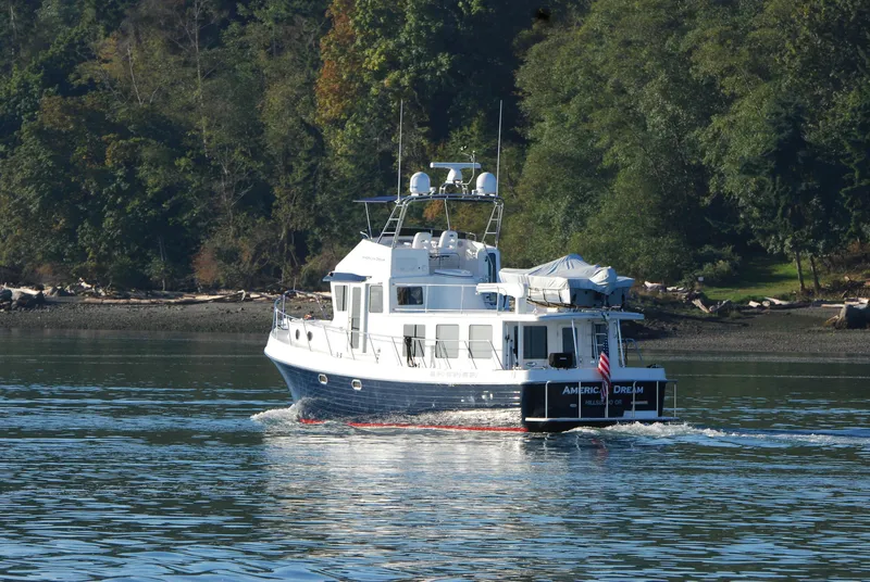 Slide: The Image of 2015 American Tug 485 cruising on a calm river with lush forest backdrop. - 4