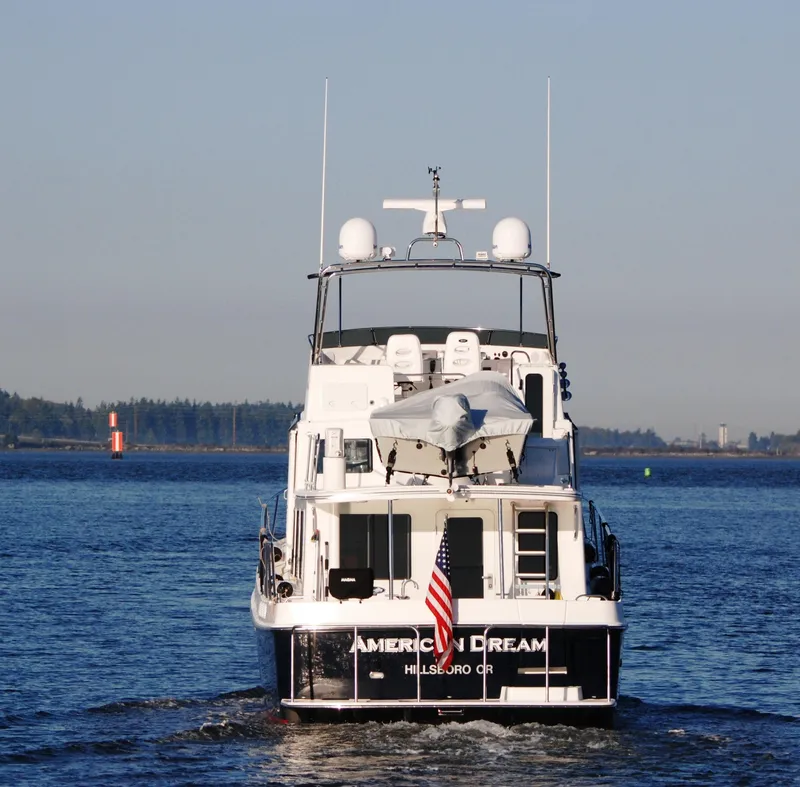 Slide: The Image of American Tug 485, 2015 model, cruising on a calm waterway with American flag. - 6