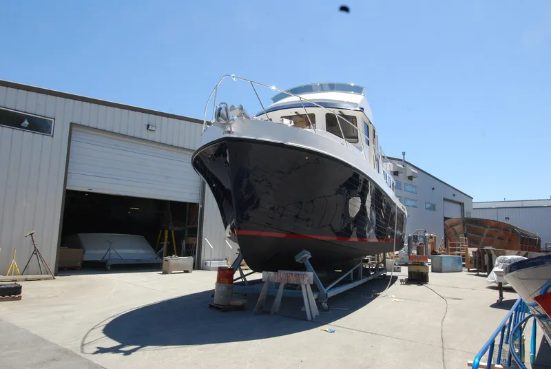 Slide: The Image of American Tug 485, 2015 model, docked outside a warehouse under clear blue skies. - 8