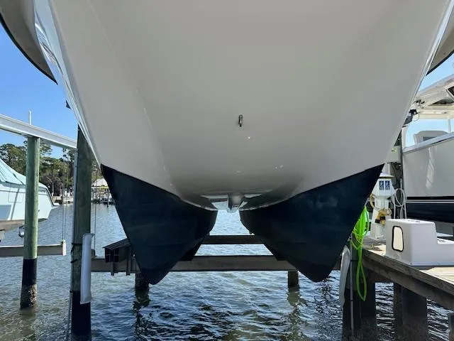 Slide: The Image of 2021 AmeraCat 27 Gen II DC catamaran hull on lift, docked by the water. - 3