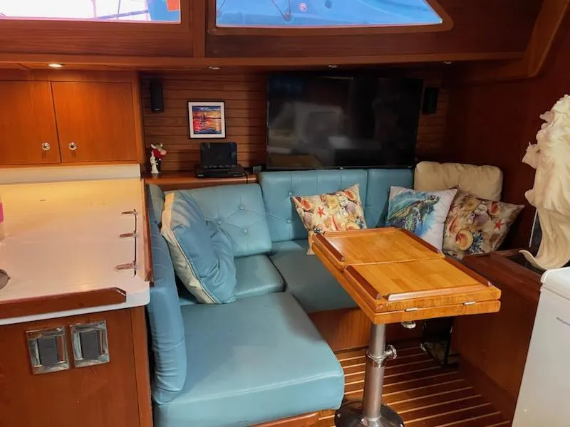Slide: The Image of Cozy interior of 2014 Seaton Custom Ketch with blue seating, wooden table, and TV. - 14