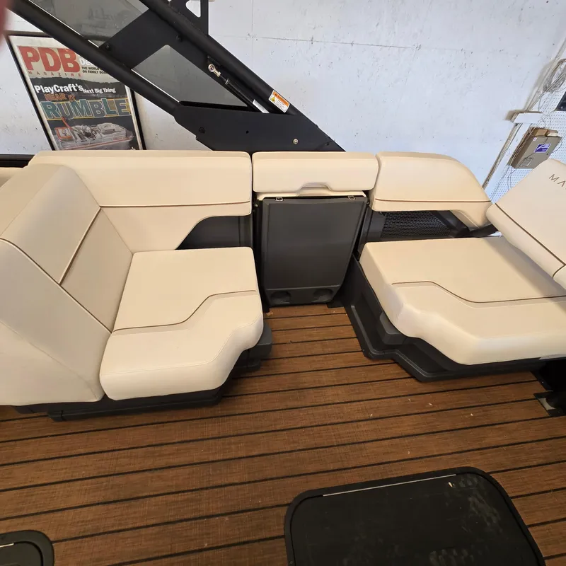 Slide: The Image of 2024 Manitou Explore 22+4 Switchback boat seating with beige upholstery on wooden deck. - 10
