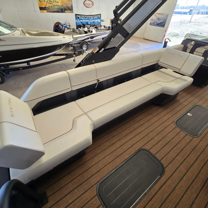 Slide: The Image of 2024 Manitou Explore 22+4 Switchback boat interior with sleek seating and wood-style flooring. - 11