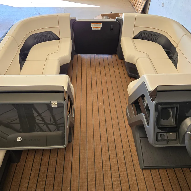 Slide: The Image of 2024 Manitou Explore 22+4 Switchback boat interior with beige seating and wood-style flooring. - 13