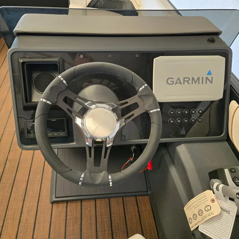 Slide: The Image of 2024 Manitou Explore 22+4 Switchback dashboard with Garmin navigation system and steering wheel. - 6