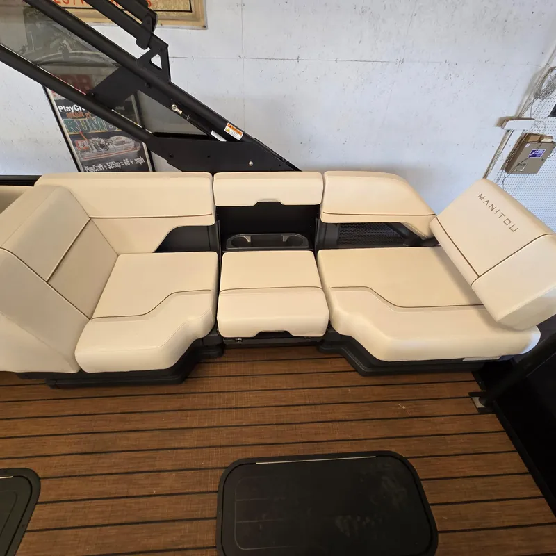 Slide: The Image of 2024 Manitou Explore 22+4 Switchback boat seating with beige upholstery and wooden deck. - 8