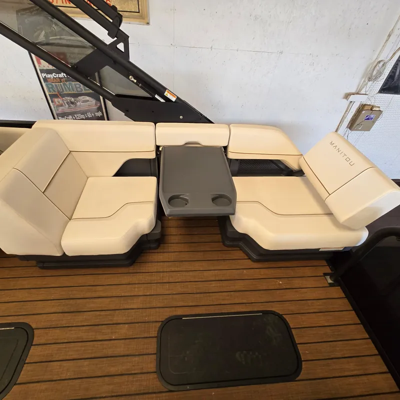 Slide: The Image of 2024 Manitou Explore 22+4 Switchback seating area with beige cushions and a central table. - 9