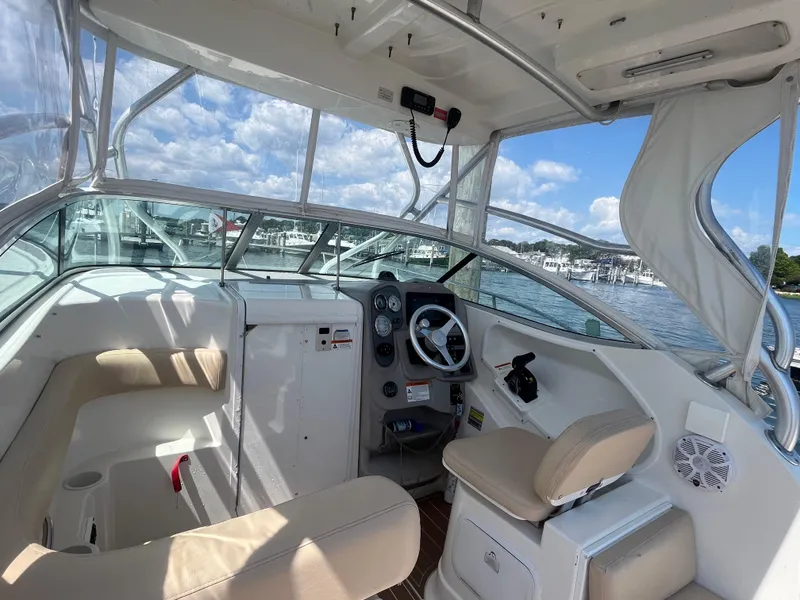 Slide: The Image of 2004 Wellcraft Coastal 252 boat interior with steering wheel, beige seating, and marina view. - 3