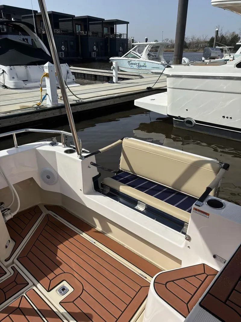 Slide: The Image of 2024 Ranger Tugs R31S boat with wooden deck and seating at a marina. - 11
