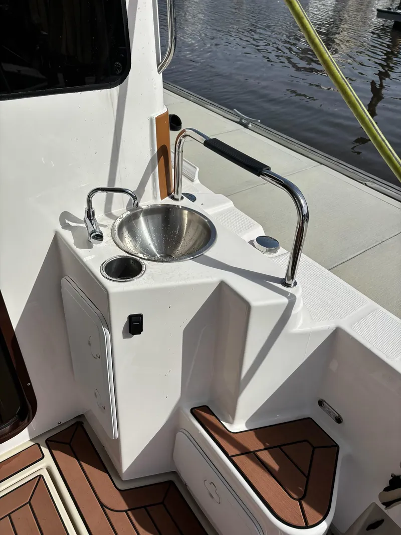 Slide: The Image of 2024 Ranger Tugs R31S boat deck with sink and wooden flooring. - 14