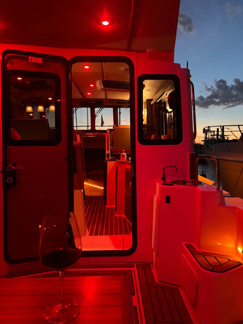 Slide: The Image of 2024 Ranger Tugs R31S boat interior with red lighting at sunset. - 15