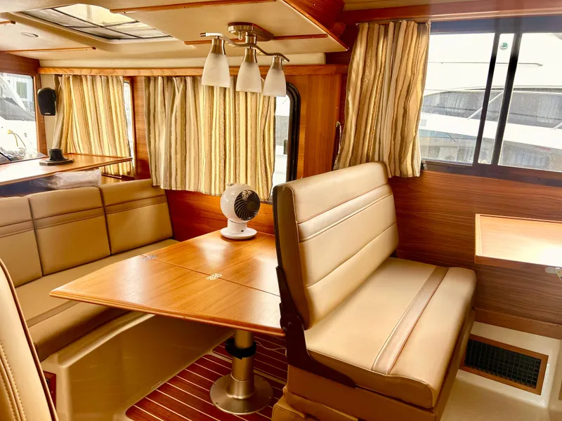 Slide: The Image of 2024 Ranger Tugs R31S interior with wood finish, dining area, and beige seating. - 17