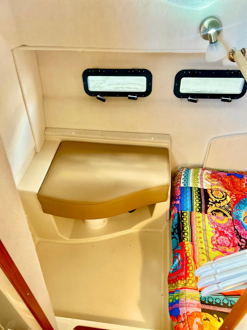 Slide: The Image of 2024 Ranger Tugs R31S interior with colorful bedding and dual windows. - 19