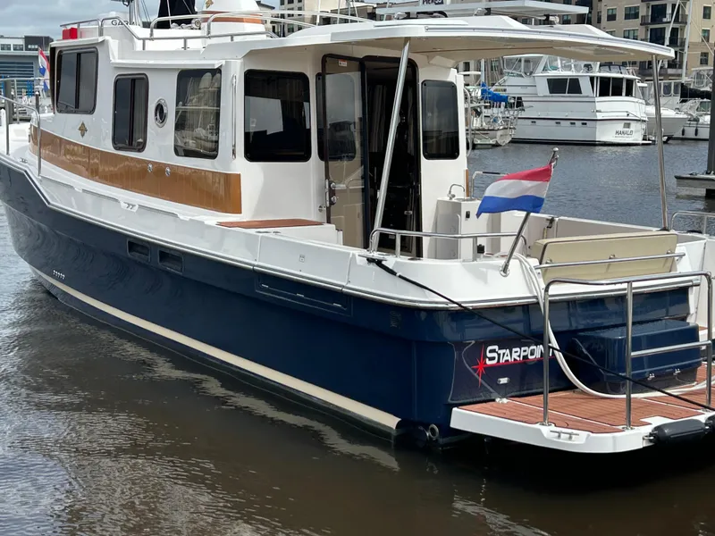 Slide: The Image of 2024 Ranger Tugs R31S boat docked in marina, featuring blue hull and wooden accents. - 22