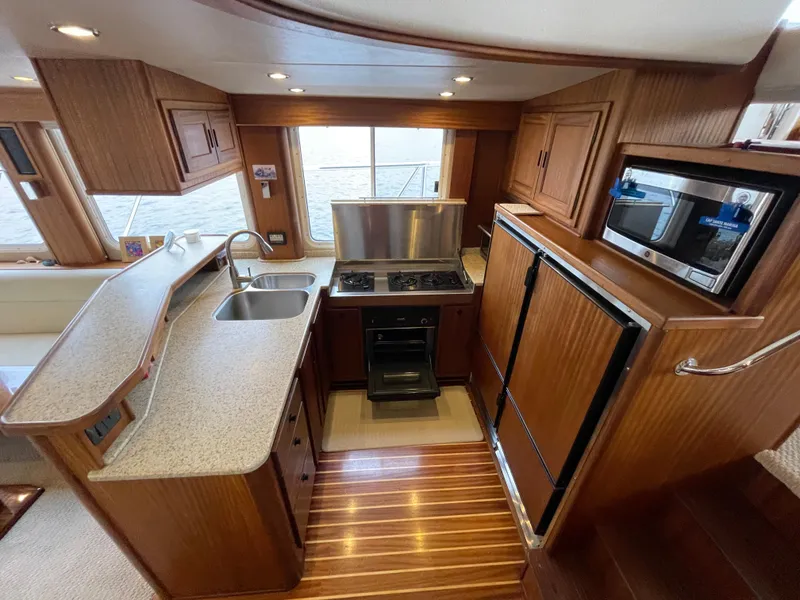 Slide: The Image of Interior of 2009 American Tug 49 Limited, featuring a modern kitchen with wood cabinetry. - 7