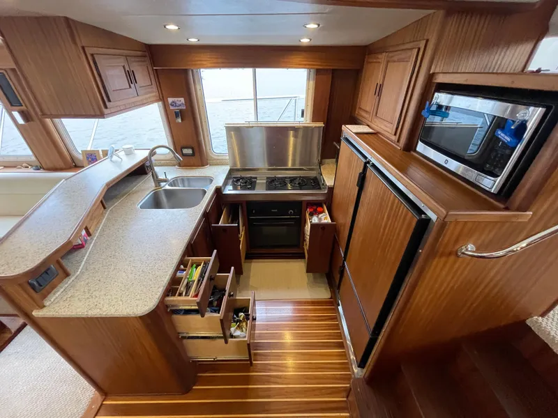 Slide: The Image of 2009 American Tug 49 Limited kitchen with wood cabinetry, stove, sink, and refrigerator. - 8