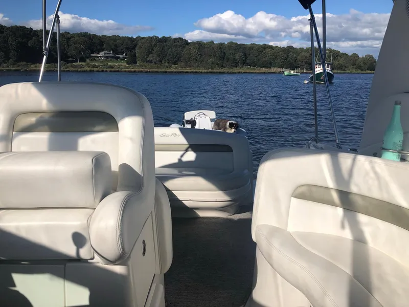 Slide: The Image of 2006 Sea Ray 320 Sundancer interior with white seating, on a calm lake under blue skies. - 15