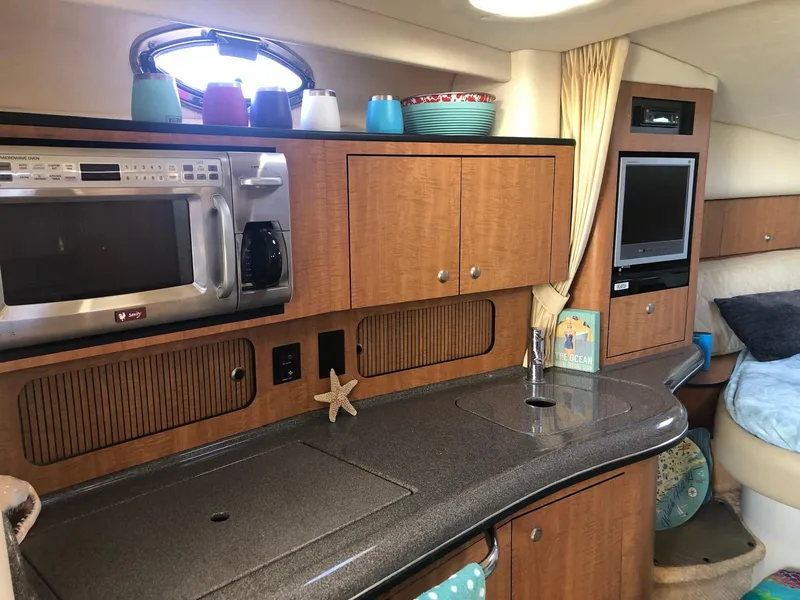 Slide: The Image of 2006 Sea Ray 320 Sundancer interior with kitchenette, microwave, and cozy seating area. - 23