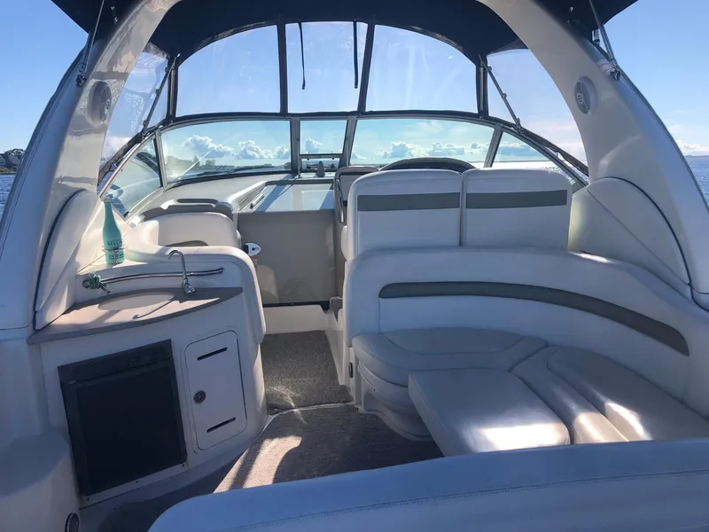 Slide: The Image of 2006 Sea Ray 320 Sundancer boat interior with seating and helm, under clear blue sky. - 9