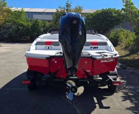 Slide: The Image of 2025 Tahoe T21 boat with outboard motor, red and white design, parked outdoors. - 11