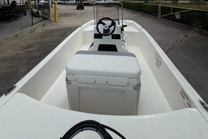 Slide: The Image of 2025 Mako Pro Skiff 15 CC boat, white interior, steering console, docked outdoors. - 4
