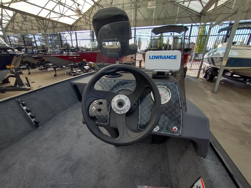 Slide: The Image of 2025 Tracker Bass Tracker Classic XL boat interior in showroom, featuring seating and controls. - 12