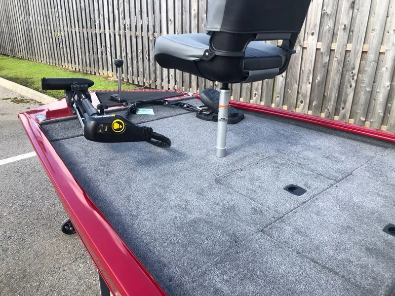 Slide: The Image of 2025 Tracker Pro 170 boat deck with seat and trolling motor, parked near wooden fence. - 6