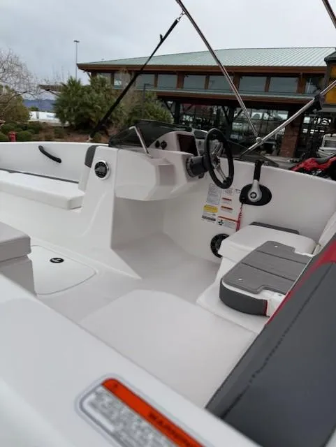 Slide: The Image of 2025 Tahoe T16 boat interior with modern steering and seating, docked near a building. - 8