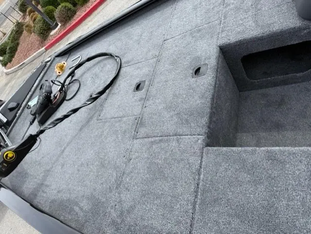 Slide: The Image of 2025 Tracker Pro 170 boat interior with gray carpet and storage compartments. - 4