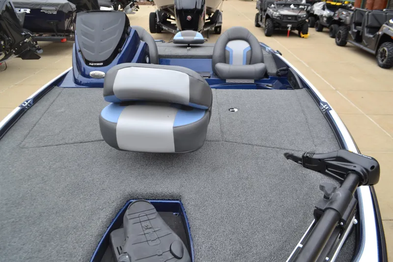 Slide: The Image of 2025 Nitro Z17 boat interior with gray and blue seating, carpeted deck, and trolling motor. - 4