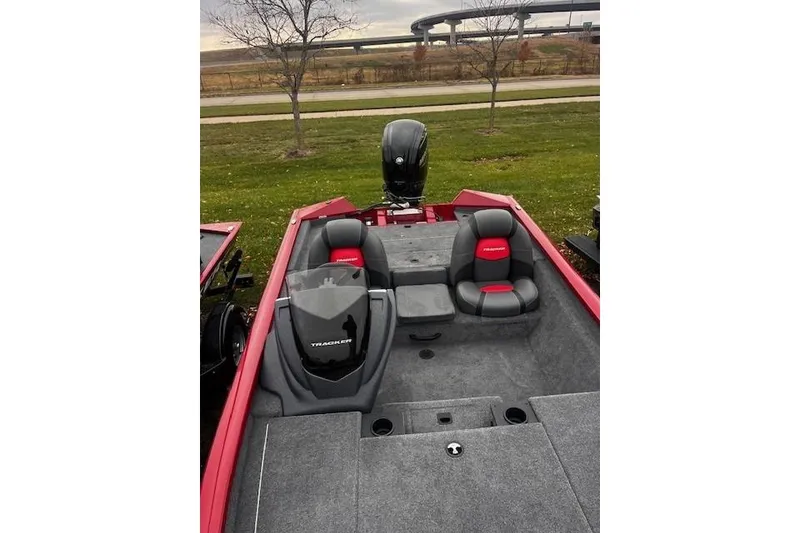 Slide: The Image of 2025 Tracker Pro Team 175 boat with red and gray seating, parked on grass. - 62