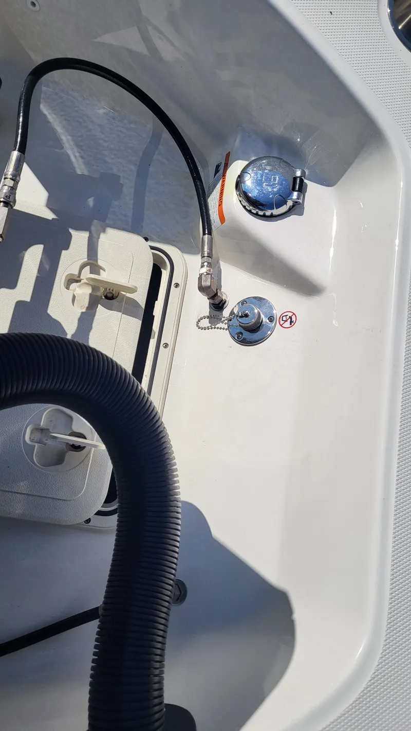 Slide: The Image of 2024 Boston Whaler 210 Montauk boat interior, showing fuel cap and hose connections. - 6