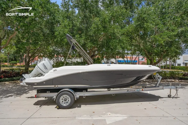 Slide: The Image of 2021 Hurricane SunDeck Sport 205 OB boat on trailer, parked outdoors with trees in background. - 0