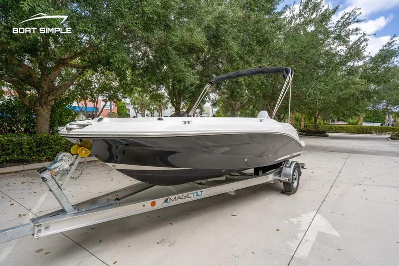 Slide: The Image of 2021 Hurricane SunDeck Sport 205 OB boat on trailer, parked outdoors with trees in background. - 6