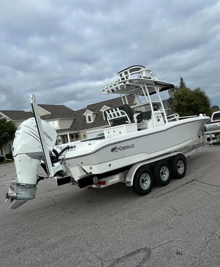 Slide: The Image of 2020 Crevalle 26 HBW boat on a trailer, parked outdoors under cloudy skies. - 2