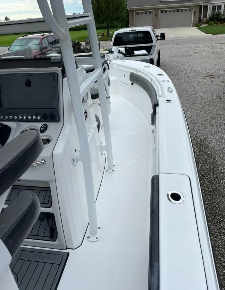Slide: The Image of 2020 Crevalle 26 HBW boat, white interior, parked near a house and truck. - 9