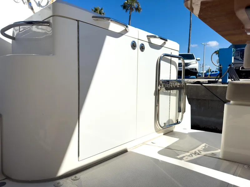 Slide: The Image of 2019 Carver C43 Coupe boat deck with storage cabinets and sunny marina backdrop. - 11