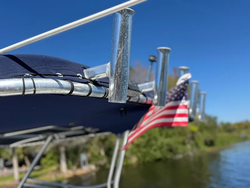 Slide: The Image of 2004 Glacier Bay Renegade 2640 boat with American flag, blue canopy, and rod holders. - 26