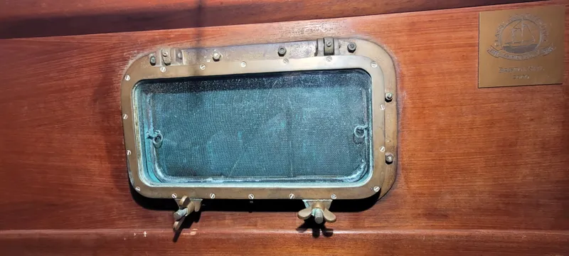 Slide: The Image of Vintage brass porthole on 1980 Shannon 38 Ketch sailboat, mounted on wooden interior. - 12