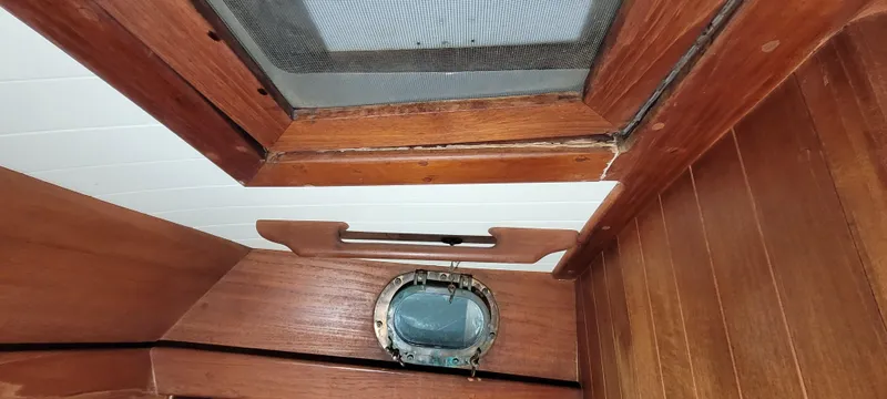 Slide: The Image of Interior view of 1980 Shannon 38 Ketch, featuring wooden paneling and a small porthole window. - 14