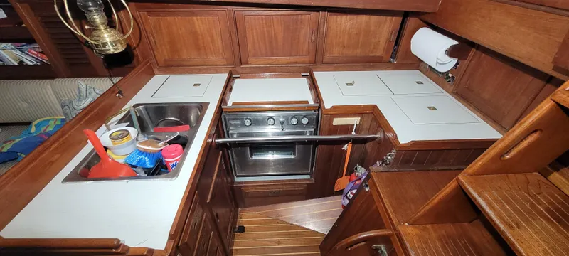 Slide: The Image of 1980 Shannon 38 Ketch galley with stove, sink, and wooden cabinetry. - 7