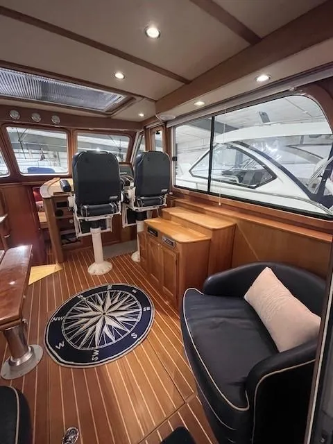 Slide: The Image of 2011 Sabre 40 Sedan interior with wood flooring, compass rug, and helm chairs. - 17