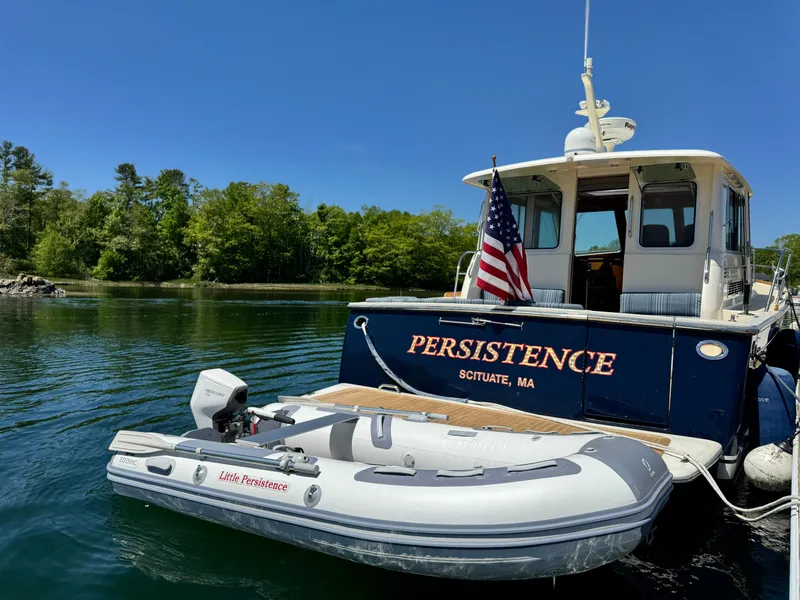 Slide: The Image of 2011 Sabre 40 Sedan yacht "Persistence" docked with inflatable boat, American flag, scenic backdrop. - 2