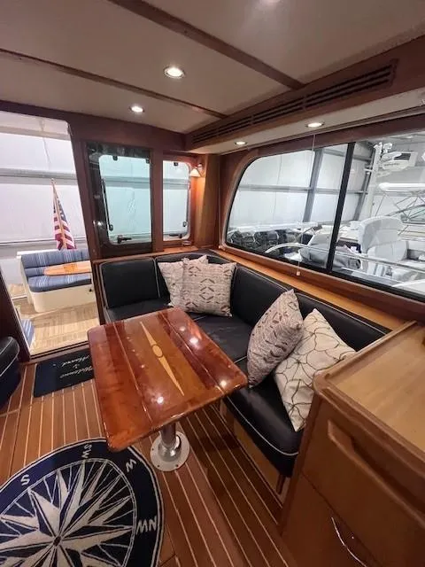 Slide: The Image of 2011 Sabre 40 Sedan interior with wooden table, cushioned seating, and nautical decor. - 20