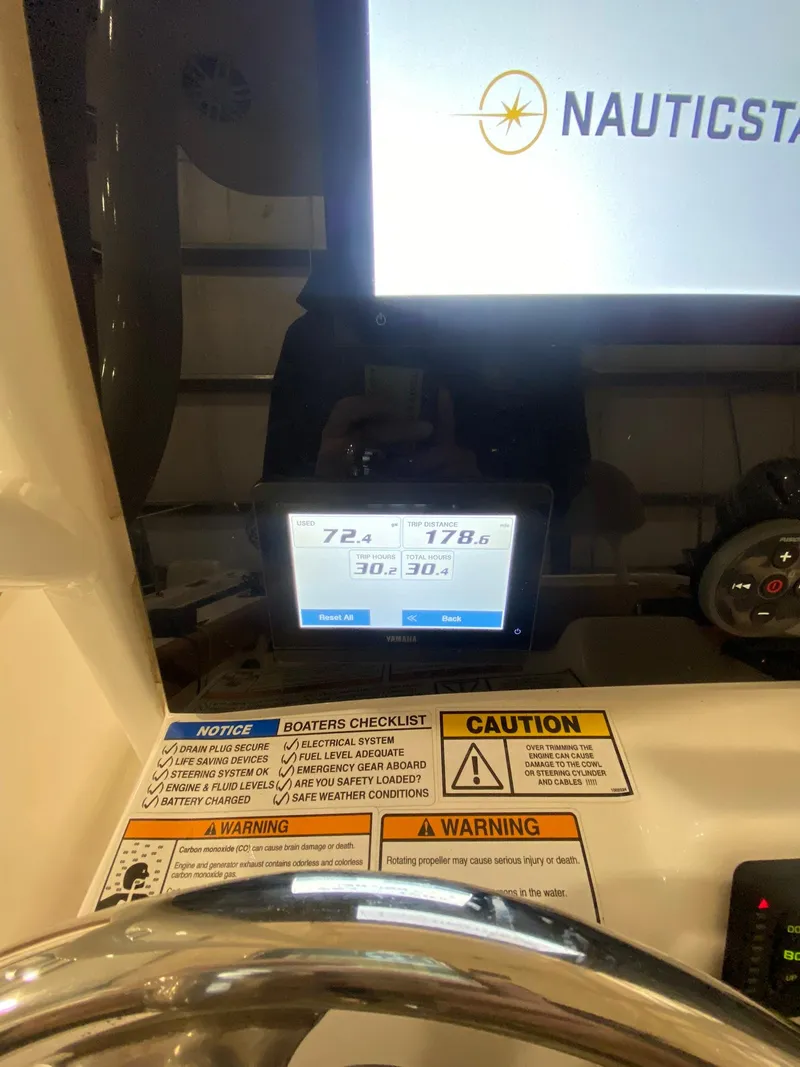 Slide: The Image of 2023 NauticStar 242L Offshore dashboard with digital display and safety warnings. - 12