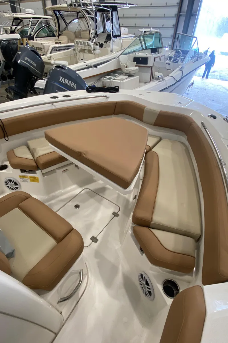 Slide: The Image of 2023 NauticStar 242L Offshore boat interior with tan seating and triangular table. - 15