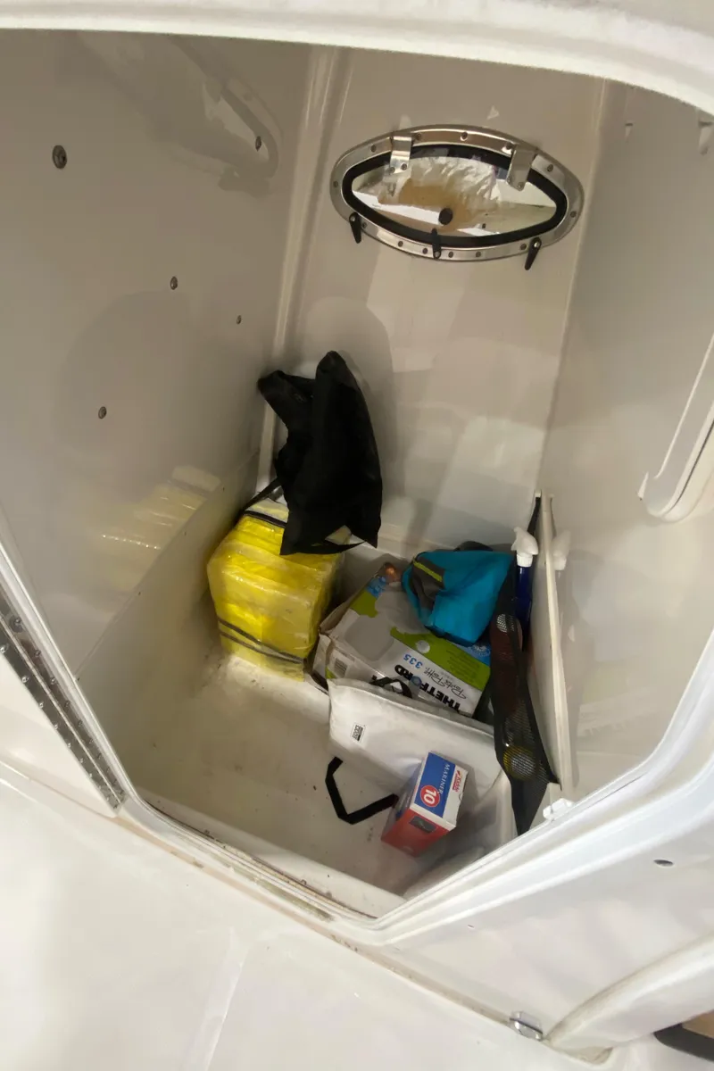 Slide: The Image of Storage compartment of 2023 NauticStar 242L Offshore boat with various items inside. - 17