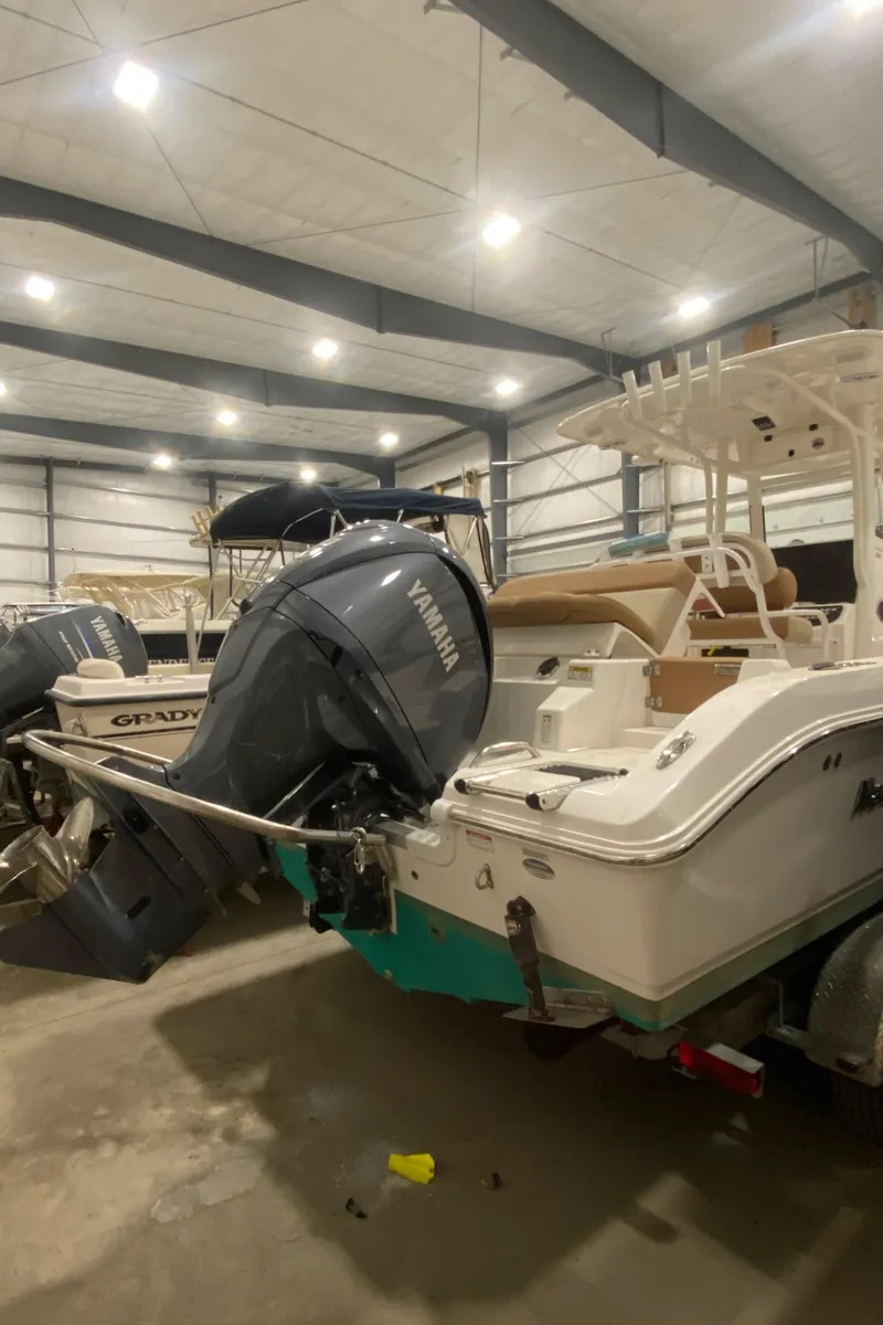 Slide: The Image of 2023 NauticStar 242L Offshore boat in storage with Yamaha outboard motor. - 2