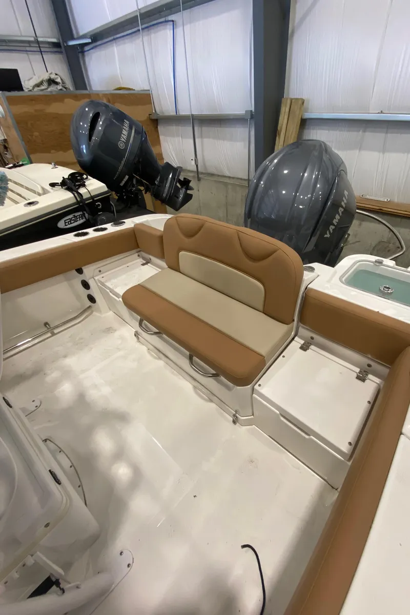 Slide: The Image of 2023 NauticStar 242L Offshore boat interior with tan seating and dual outboard motors. - 4